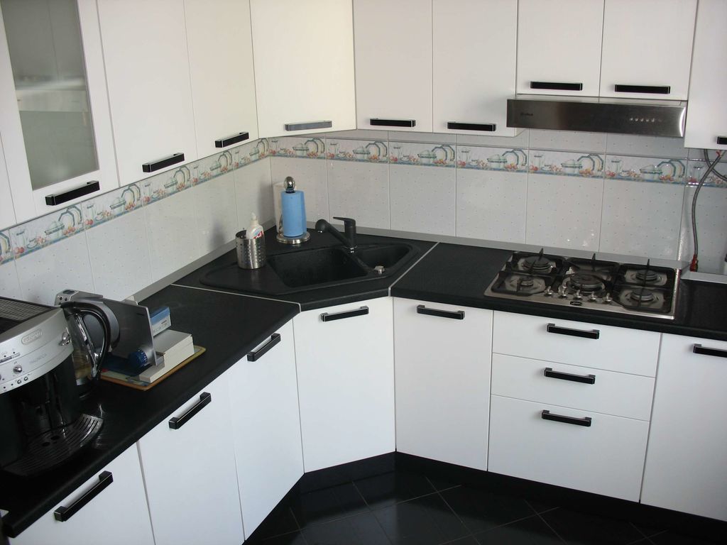Белая кухня с черной столешницей и белым фартуком фото